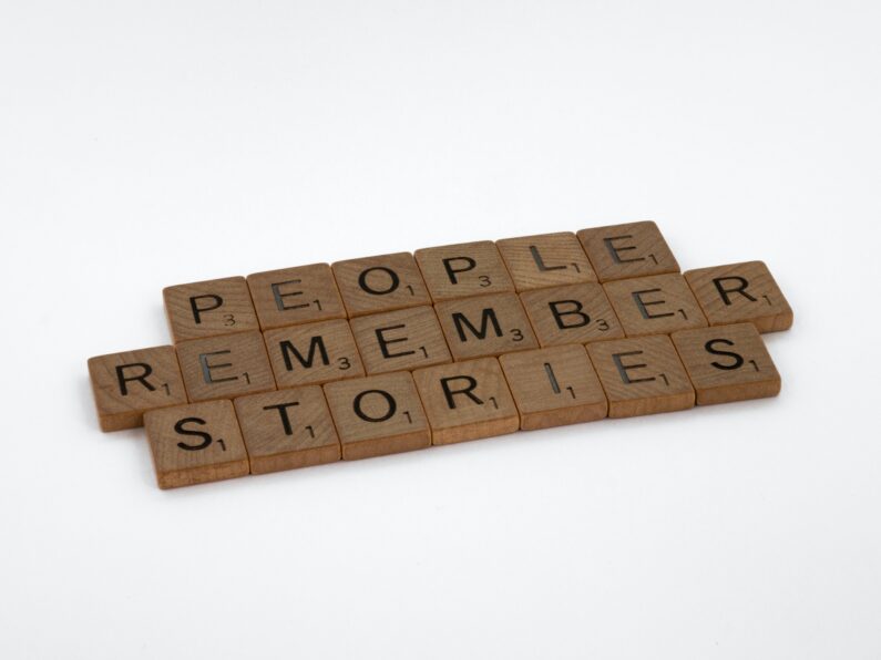 Three rows of Scrabble bricks forming the sentence People Remember Stories.